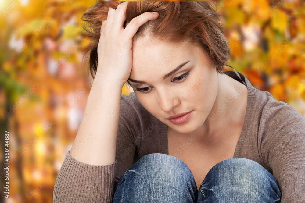 Sad young woman sits in park