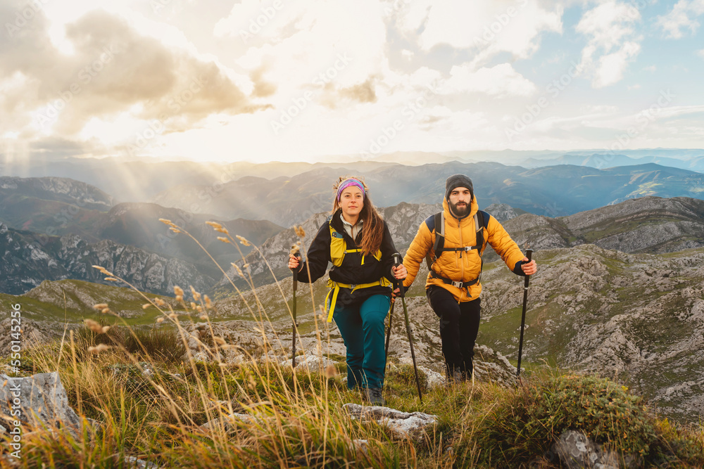 two hikers hiking in the mountains. couple of mountaineers ascending a mountain. sport and physical activity in nature.