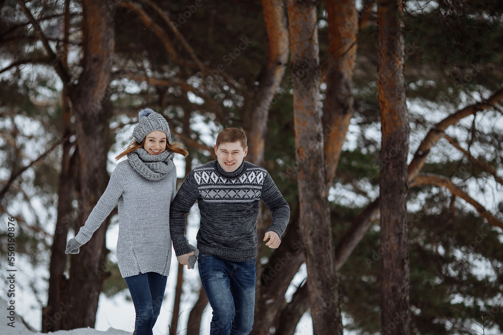 The couple runs and smiles while standing in the snow.