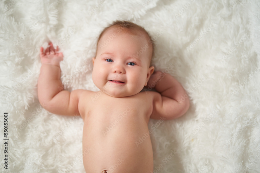Portrait of an infant on a white background, lying on his back with a joyful expression of emotion Portrait of an infant on a white background, lying on his back with a joyful expression of emotion