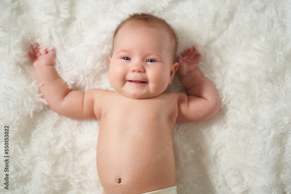 Portrait of an infant on a white background, lying on his back with a joyful expression of emotion Portrait of an infant on a white background, lying on his back with a joyful expression of emotion