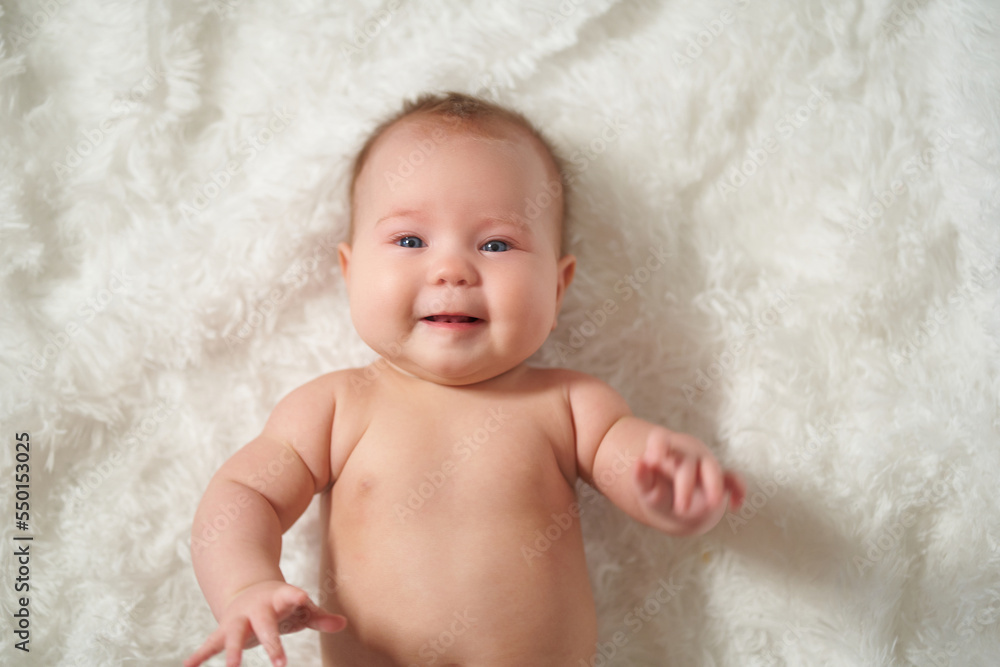 Portrait of an infant on a white background, lying on his back with a joyful expression of emotion Portrait of an infant on a white background, lying on his back with a joyful expression of emotion