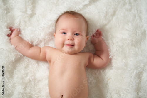 Portrait of an infant on a white background, lying on his back with a joyful expression of emotion