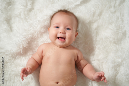 Portrait of an infant on a white background, lying on his back with a joyful expression of emotion