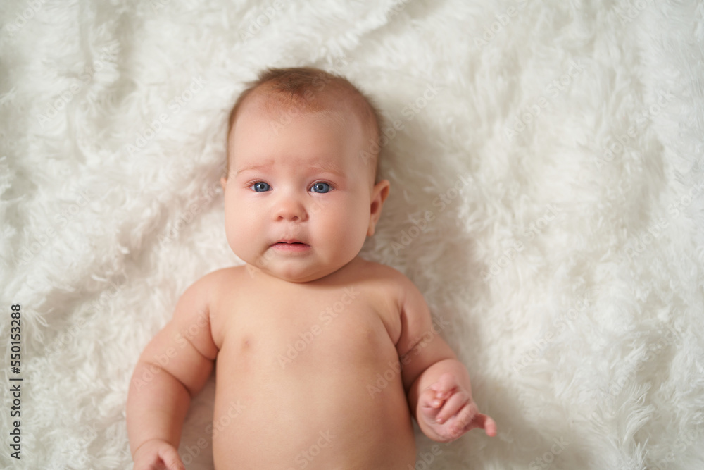portrait of an infant lying on his back on a white comforter portrait of an infant lying on his back on a white comforter