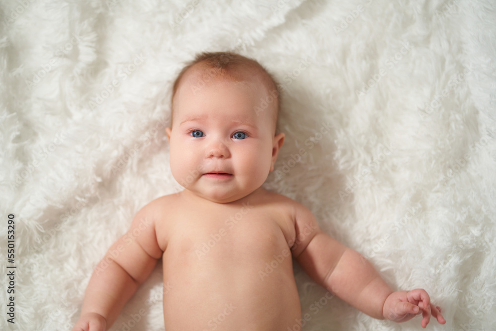 portrait of an infant lying on his back on a white comforter portrait of an infant lying on his back on a white comforter