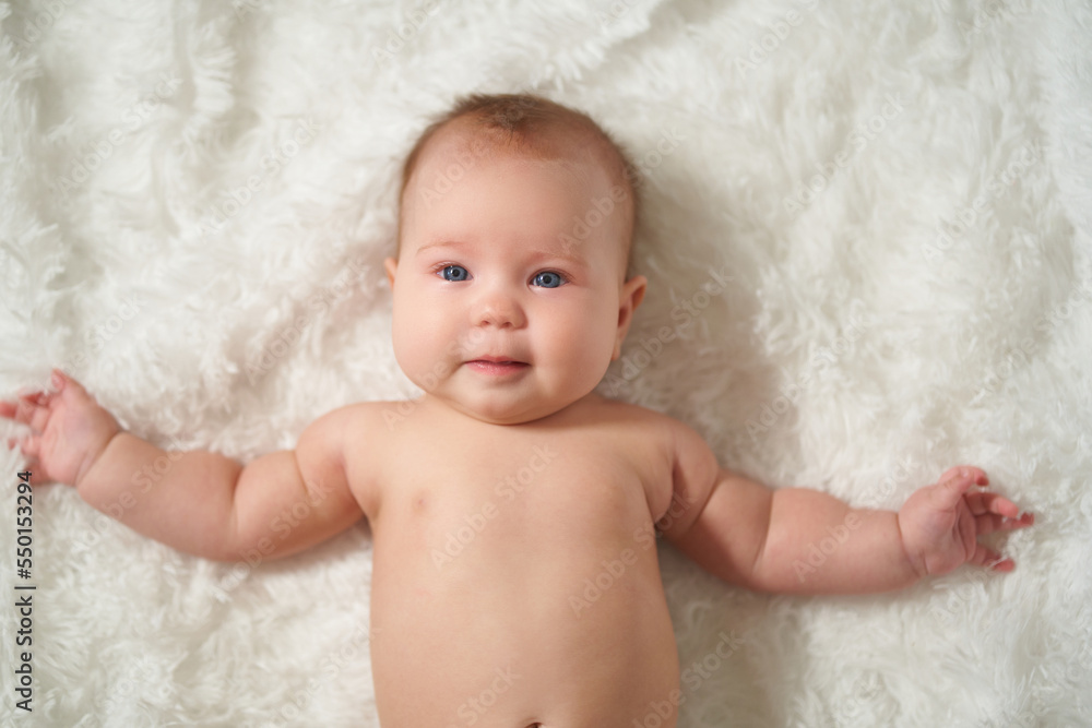 portrait of an infant lying on his back on a white comforter portrait of an infant lying on his back on a white comforter