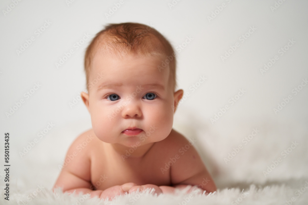 portrait of an infant with serious emotion lying on his belly against a white background portrait of an infant with serious emotion lying on his belly against a white background