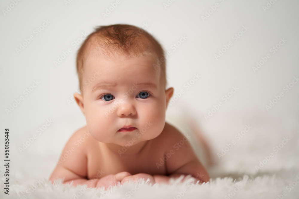 portrait of an infant with serious emotion lying on his belly against a white background portrait of an infant with serious emotion lying on his belly against a white background