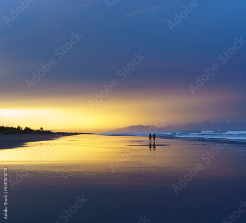 Couple walking beach at sunrise