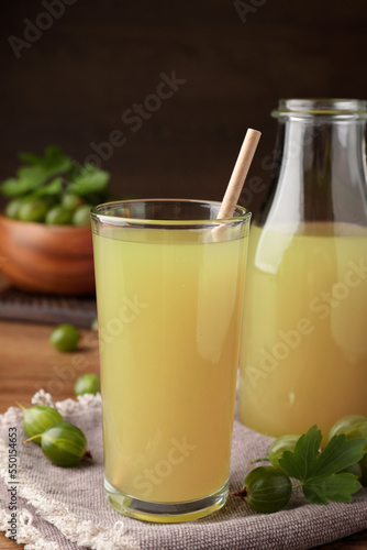 Tasty gooseberry juice on wooden table, closeup