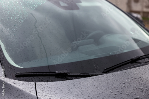 Car wipers cleaning water drops from windshield glass outdoors  closeup