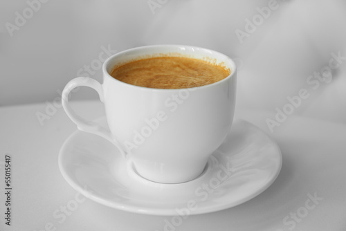 Cup of delicious aromatic coffee on white table indoors, closeup © New Africa