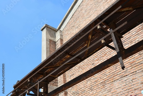 Low angle shot of rusty iron structure attached on the brick wall of the building in Erqi factory photo