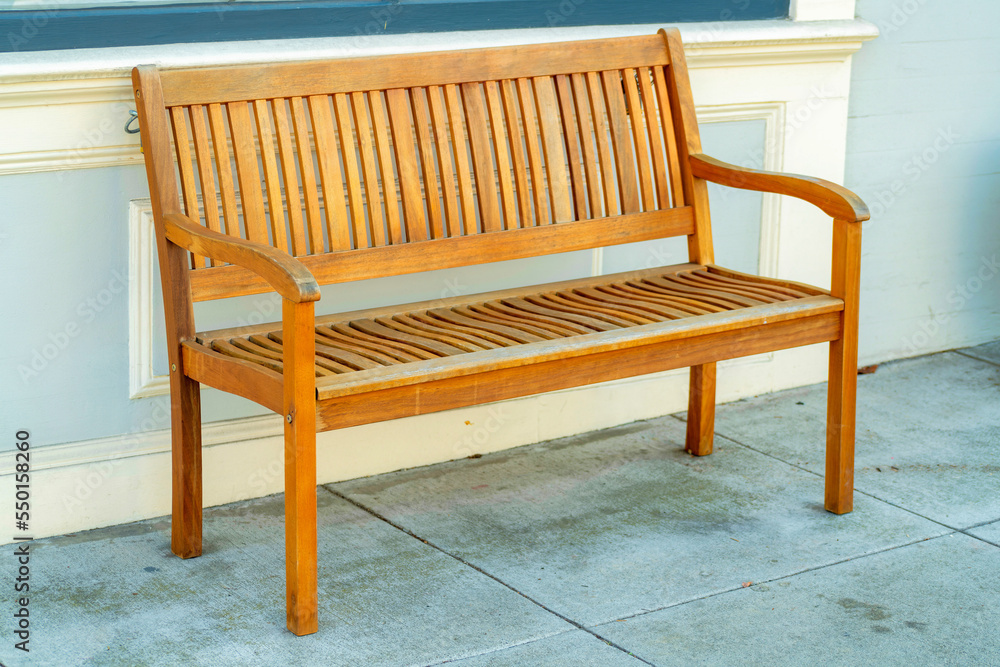 Brown wooden bench with beige stucco wall background on cement in urban area of the city Brown wooden bench with beige stucco wall background on cement in urban area of the city
