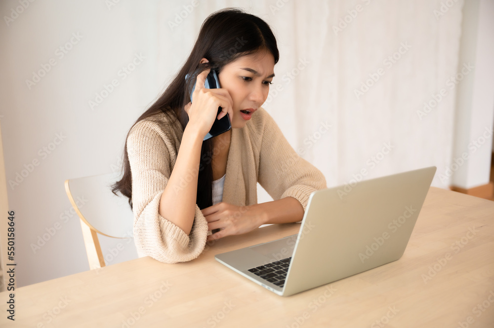 Young asian woman talking mobile smartphone while working on computer laptop at house. Work at home, Video conference, Video calling Young asian woman talking mobile smartphone while working on computer laptop at house. Work at home, Video conference, Video calling