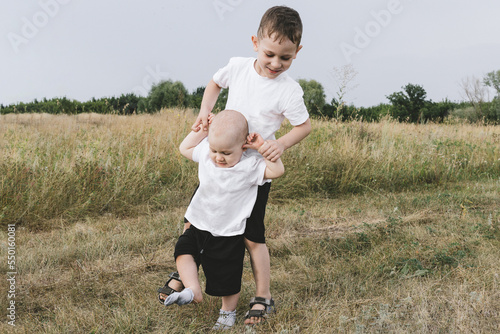 Konstfotografi Two playful caucasian brother children enjoy having fun playing together at green grass lawn summer day