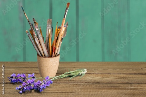 Set of paint brushes and lavender flower on desk