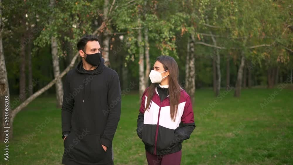 Young beautiful woman and handsome man wearing masks and walking in the sunny park. Young beautiful woman and handsome man wearing masks and walking in the sunny park.