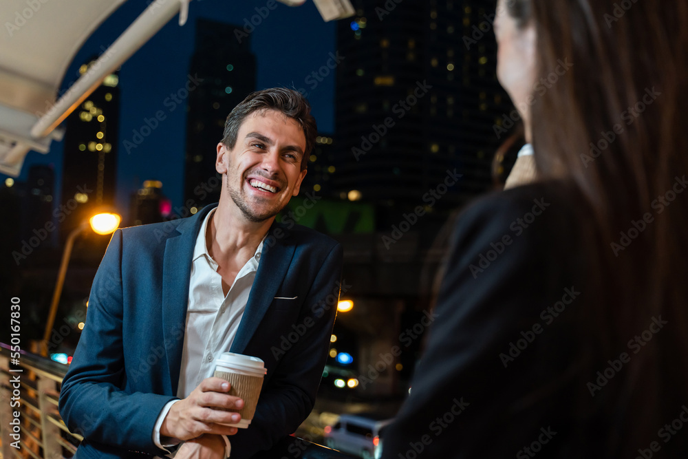 Caucasian young businessman and woman stand outdoor in city at night. 