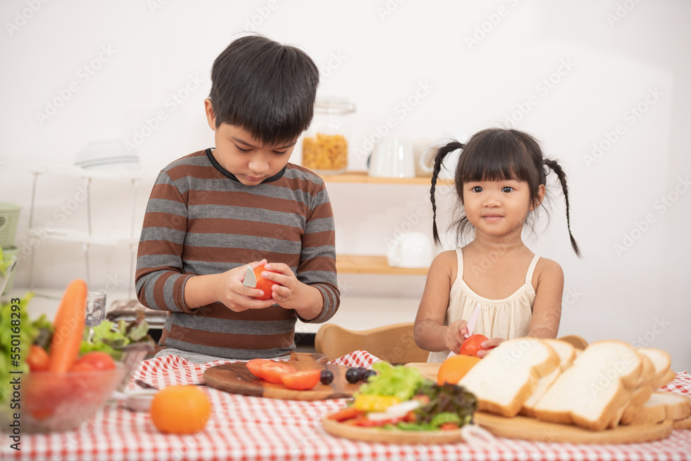 Happy children prepares and eats vegetable salad in kitchen. The concept of healthy diet and lifestyle. Vegan food and healthy lifestyle.Selective Focus. Happy children prepares and eats vegetable salad in kitchen. The concept of healthy diet and lifestyle. Vegan food and healthy lifestyle.Selective Focus.