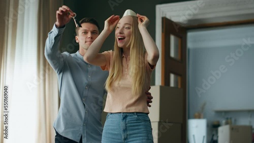 Man surprising woman showing keys from new apartment. Girl rejoicing moving home