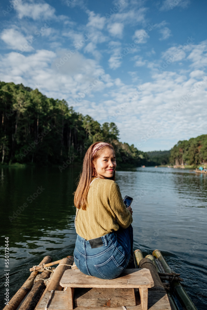 Asian woman smile and sitting on a bamboo raft in the lake in the morning, relaxing, People freedom style. Asian woman smile and sitting on a bamboo raft in the lake in the morning, relaxing, People freedom style.