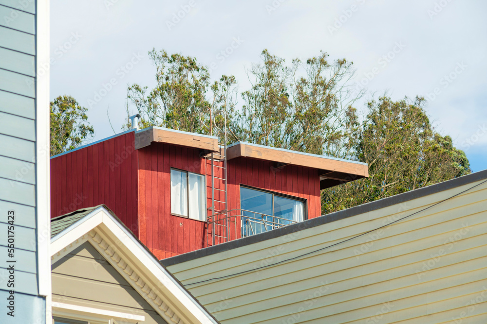 Red house in detail shot with exterior timber or wood facade and other building details in foreground midday in sun Red house in detail shot with exterior timber or wood facade and other building details in foreground midday in sun