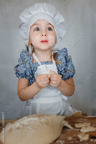 surprised little girl in the kitchen in a red chef's hat