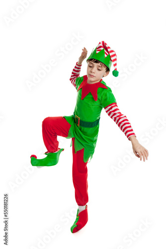 Full length portrait of an adorable 10 year old boy dressed in a Christmas elf costume dancing, isolated on a white background