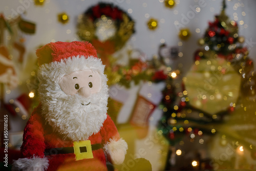 Plush Santa Claus toy with blurred Christmas background.