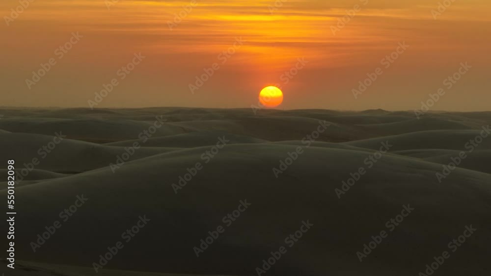 Dramatic aerial panning shot of the sun low on the horizon with sand dunes and a slightly hazy sky, Northern Brazil Dramatic aerial panning shot of the sun low on the horizon with sand dunes and a slightly hazy sky, Northern Brazil