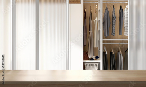 Wooden table top, countertop in modern, luxury design walk in wardrobe closet with woman’s dress cloth in bedroom with reeded glass door partition for lifestyle, personal product display background