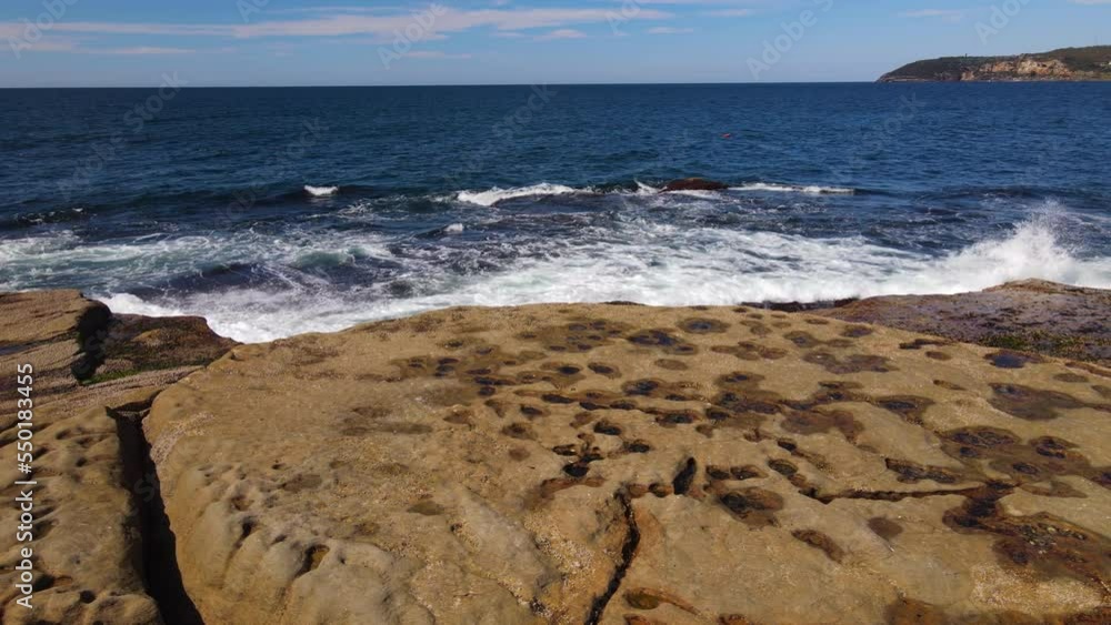 Waves crash on rocks slow drone pan and raise Waves crash on rocks slow drone pan and raise