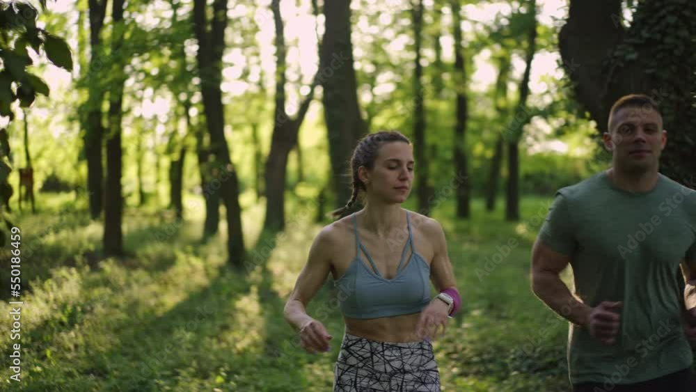 Woman and man running in the forest. Slow motion. Healthy lifestyle concept.