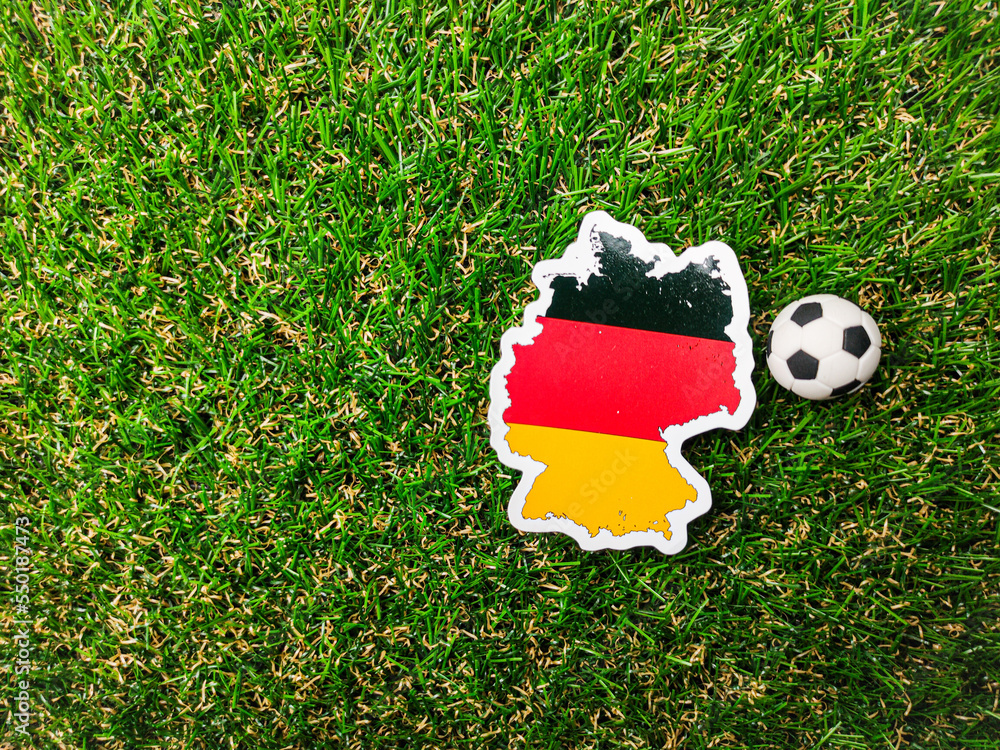 Fototapeta premium A ball and German flag sticker is on a green field.