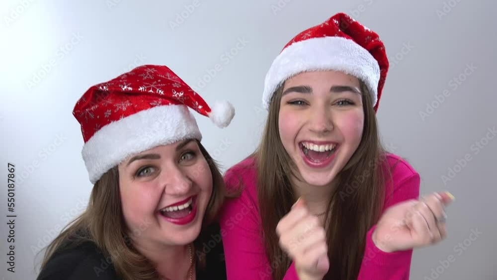Screaming and jumping with a thumbs up and dance Christmas video positive emotions mom and daughter rejoice in the holiday wear red Christmas hats New Year's party at home friendship joy fun Screaming and jumping with a thumbs up and dance Christmas video positive emotions mom and daughter rejoice in the holiday wear red Christmas hats New Year's party at home friendship joy fun