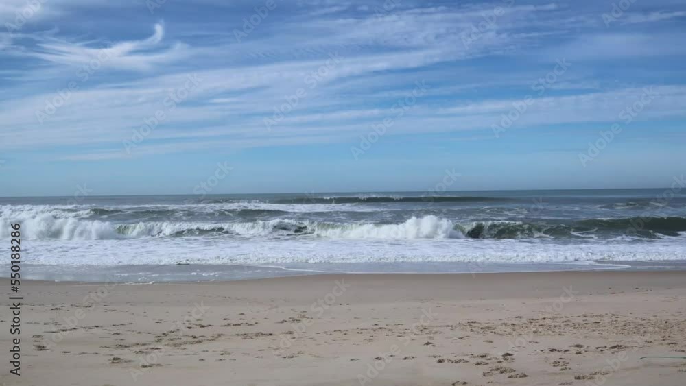 Waves behind the beach with footprints in the sand Waves behind the beach with footprints in the sand