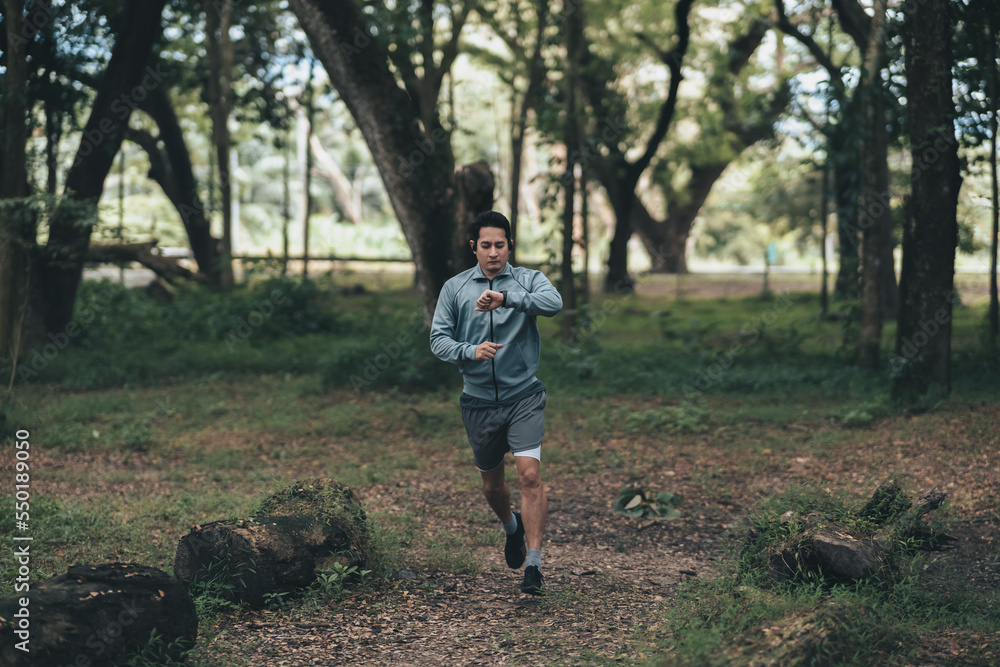 Obraz premium sport man checking at smartwatch during training and running in the park. Outdoor workout, Healthy lifestyle concept.