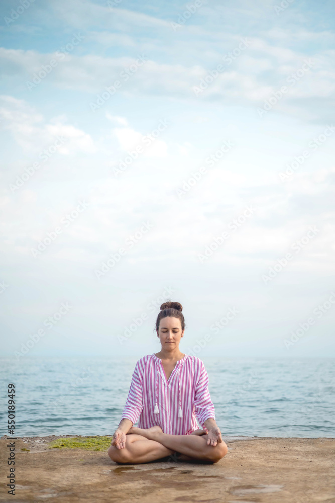 Yoga woman meditation prayer hands namaste overhead lotus position sitting sand sky beach landscape