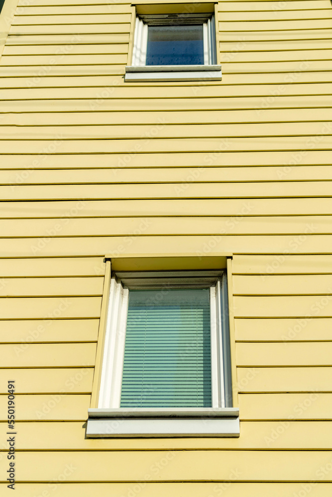 Fototapeta premium Horizontally slatted wood house facade with white accent paint around two hidden windows on the exterior of building