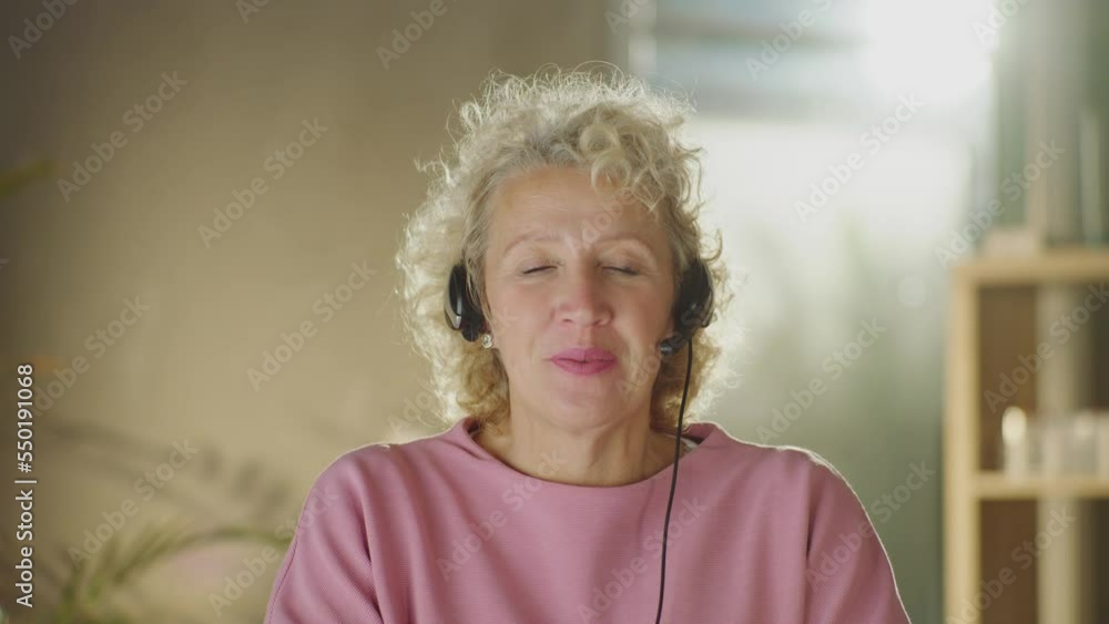 Mature businesswoman wearing headset talking to the camera in video conference chat. Female boss speaking during an online meeting Mature businesswoman wearing headset talking to the camera in video conference chat. Female boss speaking during an online meeting