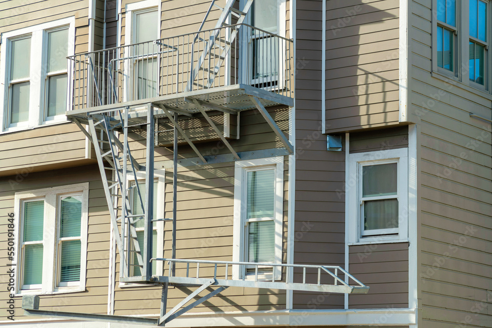 Gray metal fire escape ladder on exterior of modern building in a major city or in a downtown region Gray metal fire escape ladder on exterior of modern building in a major city or in a downtown region