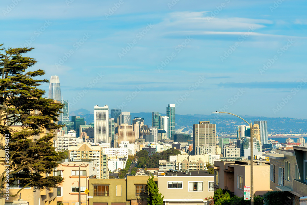 Downtown city of San Francisco California with rows of modern houses and buildings with mountains and blue sky background