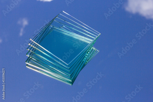 Clear glass from the factory of various sizes arranged in several sheets placed on the glass reflecting the sky.Glass is a recyclable building material.