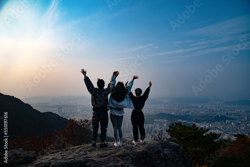 three friends standing on the big rock at mountain