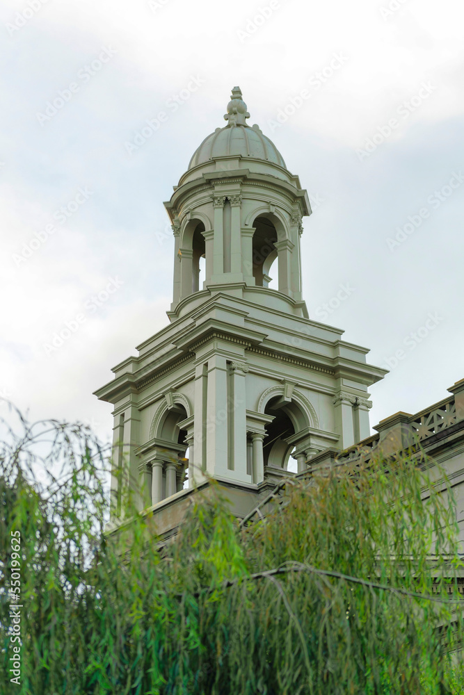 Fototapeta premium Hollow cement church steeple with hidden garden trees in a secret church courtyard on the edge of suburban city