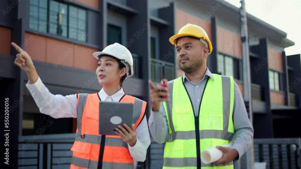 Serious two engineer man Using tablet for checking and maintenance to inspection at modern home building construction. Two architect looking forward with white safety helmet in construction site. Serious two engineer man Using tablet for checking and maintenance to inspection at modern home building construction. Two architect looking forward with white safety helmet in construction site.