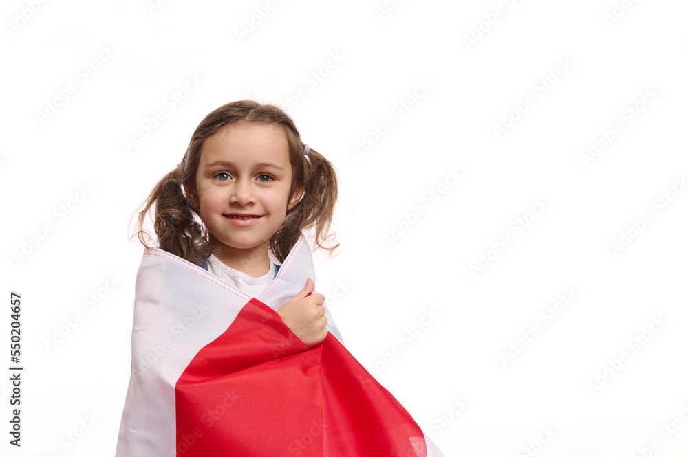 European little girl with two cute ponytails wrapping Poland flag, smiling cheerful toothy smile looking at camera, isolated on white background. Celebration of Polish Independence Day, November 11th European little girl with two cute ponytails wrapping Poland flag, smiling cheerful toothy smile looking at camera, isolated on white background. Celebration of Polish Independence Day, November 11th