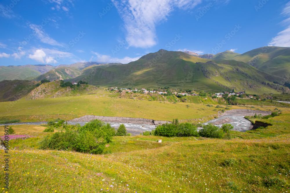 A beautiful mountain landscape with a small meandering river and a blue sky. Mountainous Georgia.